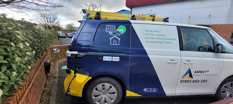 A service van advertising solar panels, battery storage, electric vehicle chargers, and air source heat pumps, parked on a street.